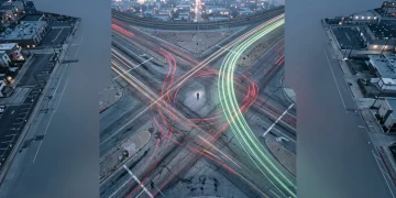 Aerial view of a person at a chaotic city intersection with contrasting green and red light trails representing financial decisions, illustrating investment dogma versus debt repayment.